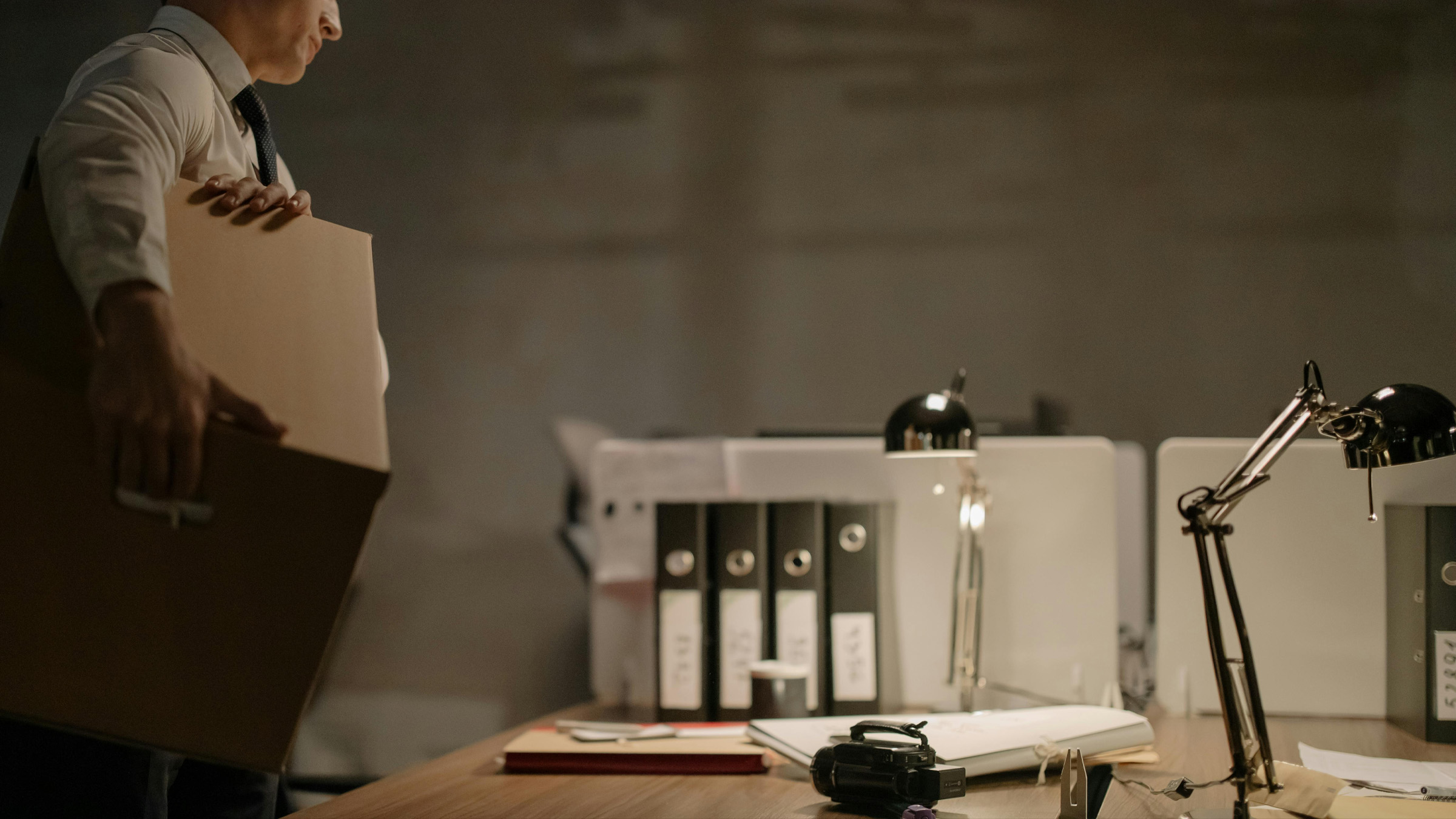 An empty desk with a sticky note pad and a packed file box